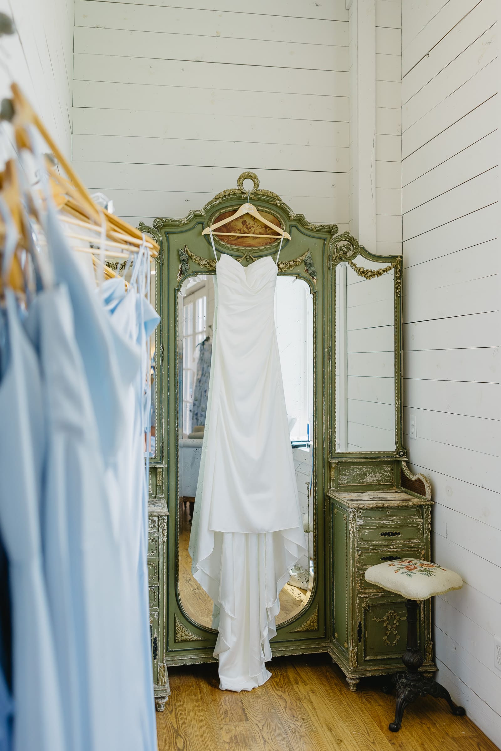 Wedding dress hanging beside an antique mirror at The Barn at Paradise Place