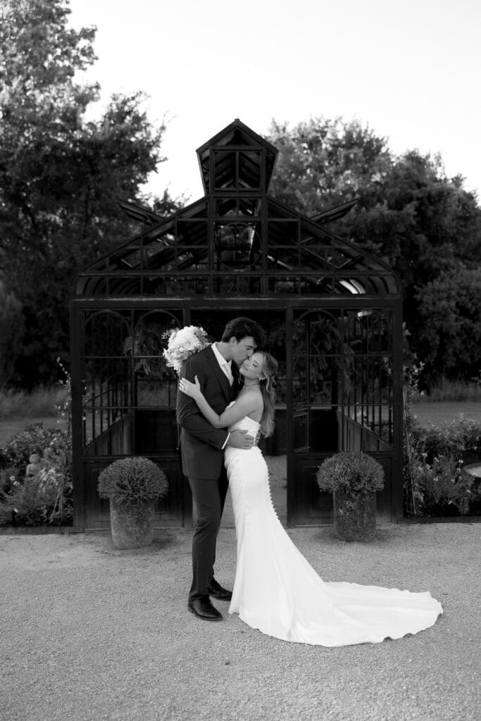 Bride and groom posing by the black greenhouse at The Barn at Paradise Place