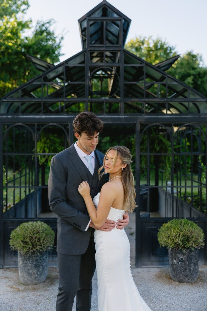 Bride and groom during romantic wedding portraits by the black greenhouse