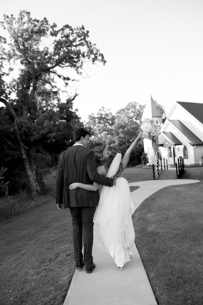 Black and white portrait of the newlyweds walking together after their ceremony