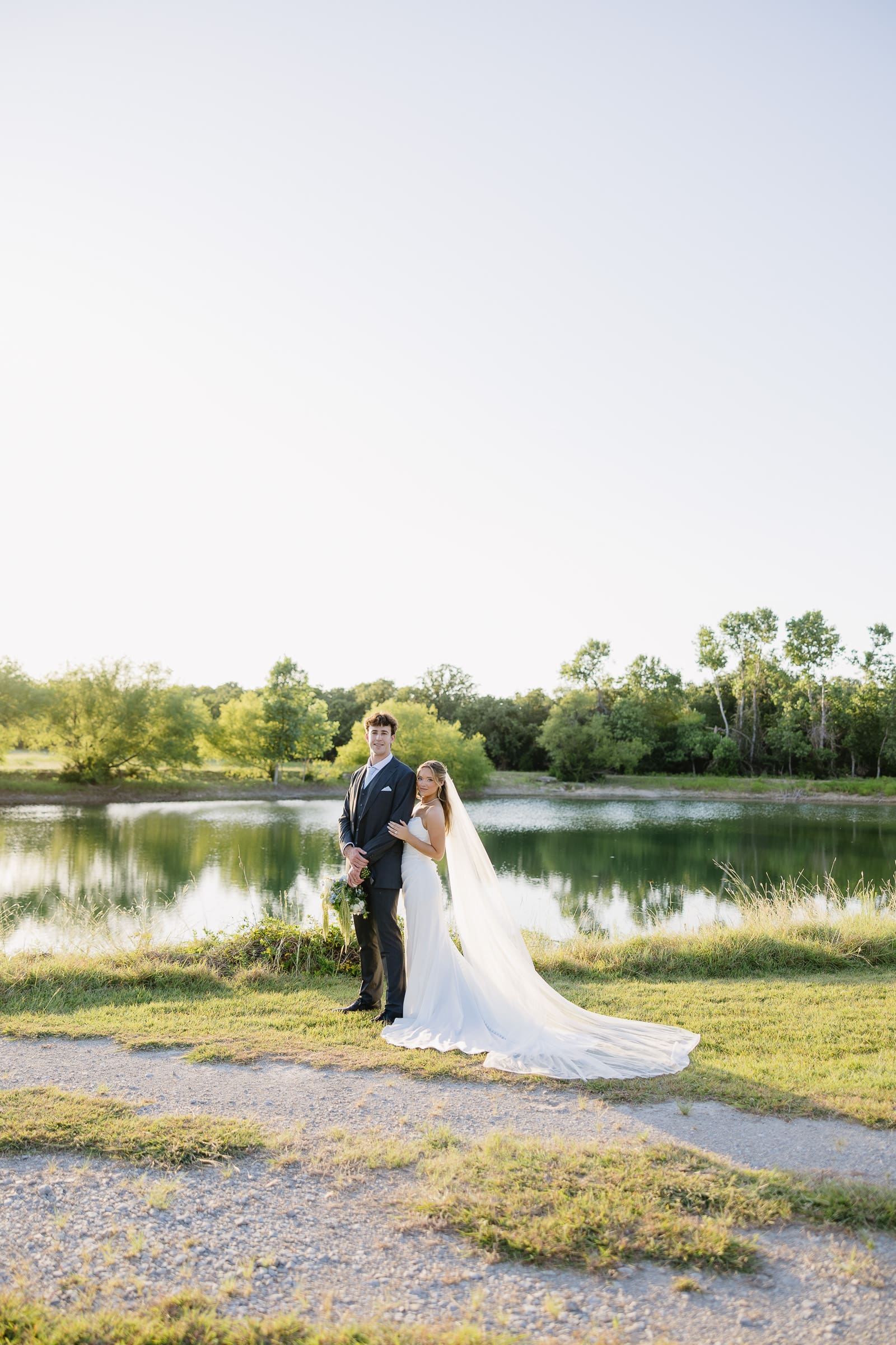 Bride and groom taking golden-hour portraits by the pond at The Barn at Paradise Place