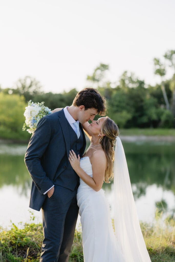 Bride and groom embracing during golden hour wedding portraits by the water