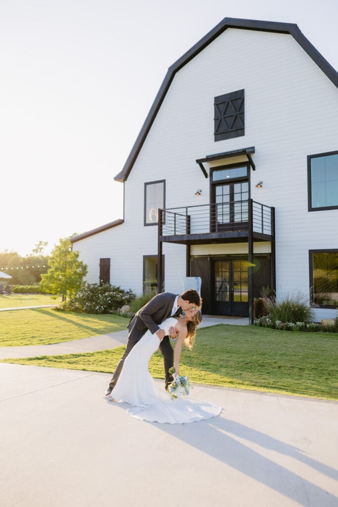 Bride and groom sharing a romantic dip in front of The Barn at Paradise Place