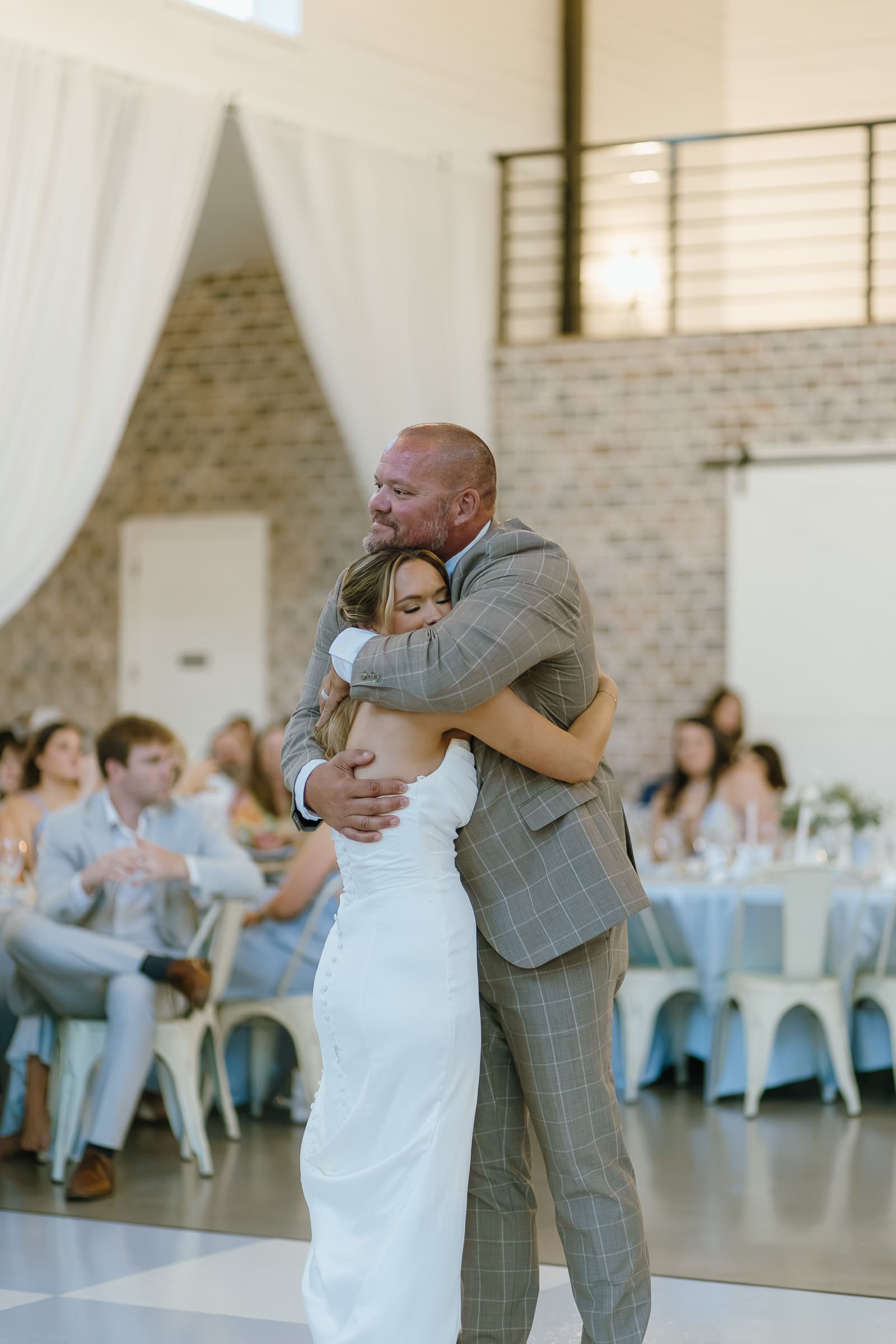 Bride hugging a loved one during her wedding reception at The Barn at Paradise Place