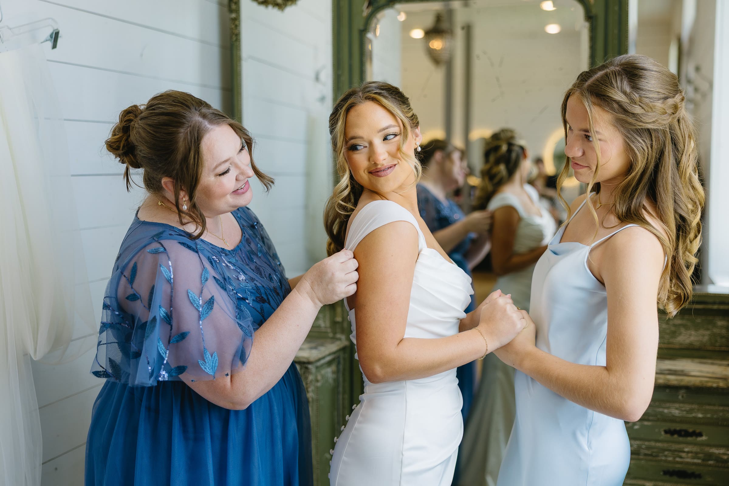 Bride getting ready with her mom and sister before the wedding ceremony