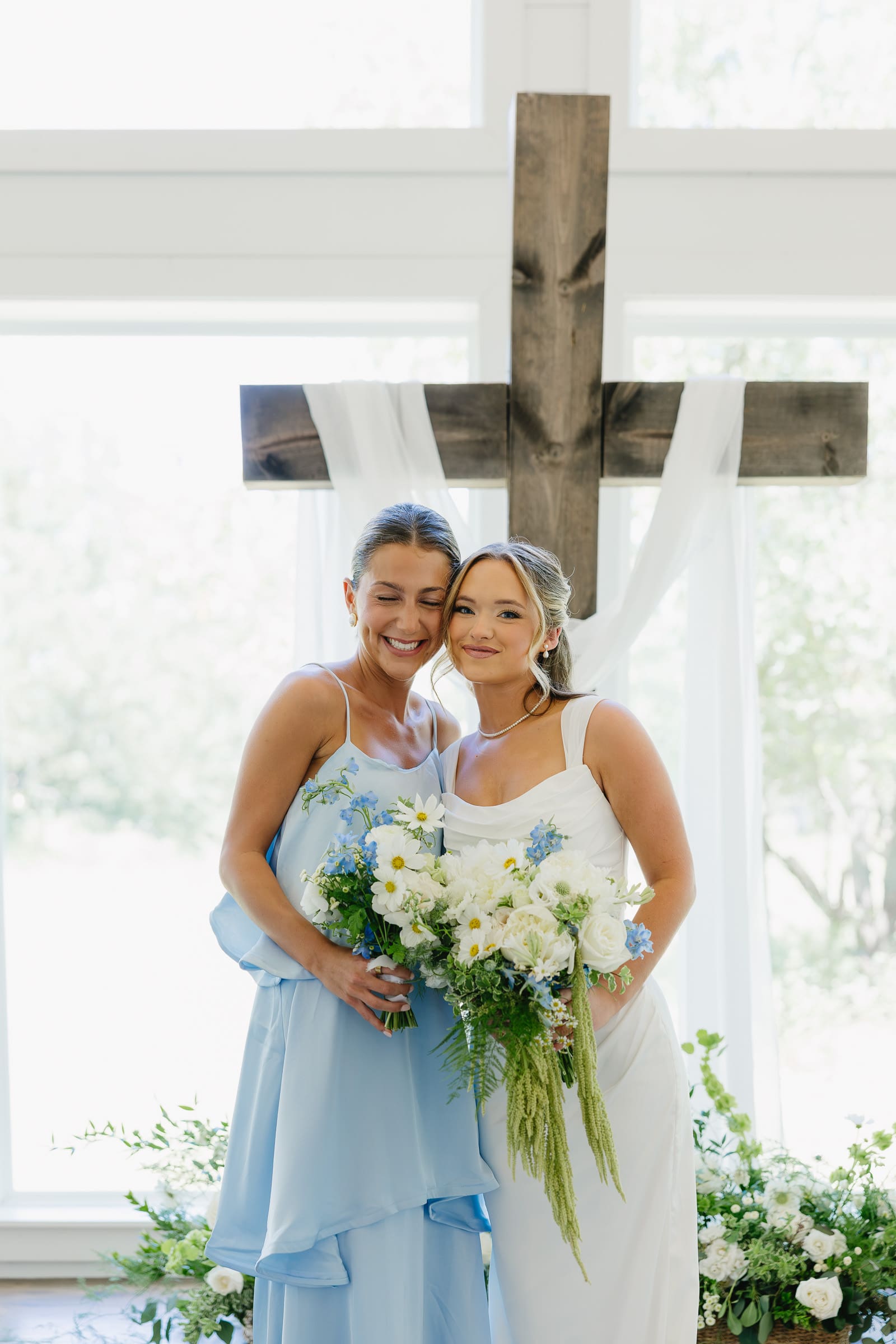 Bride posing with a bridesmaid in a soft blue dress