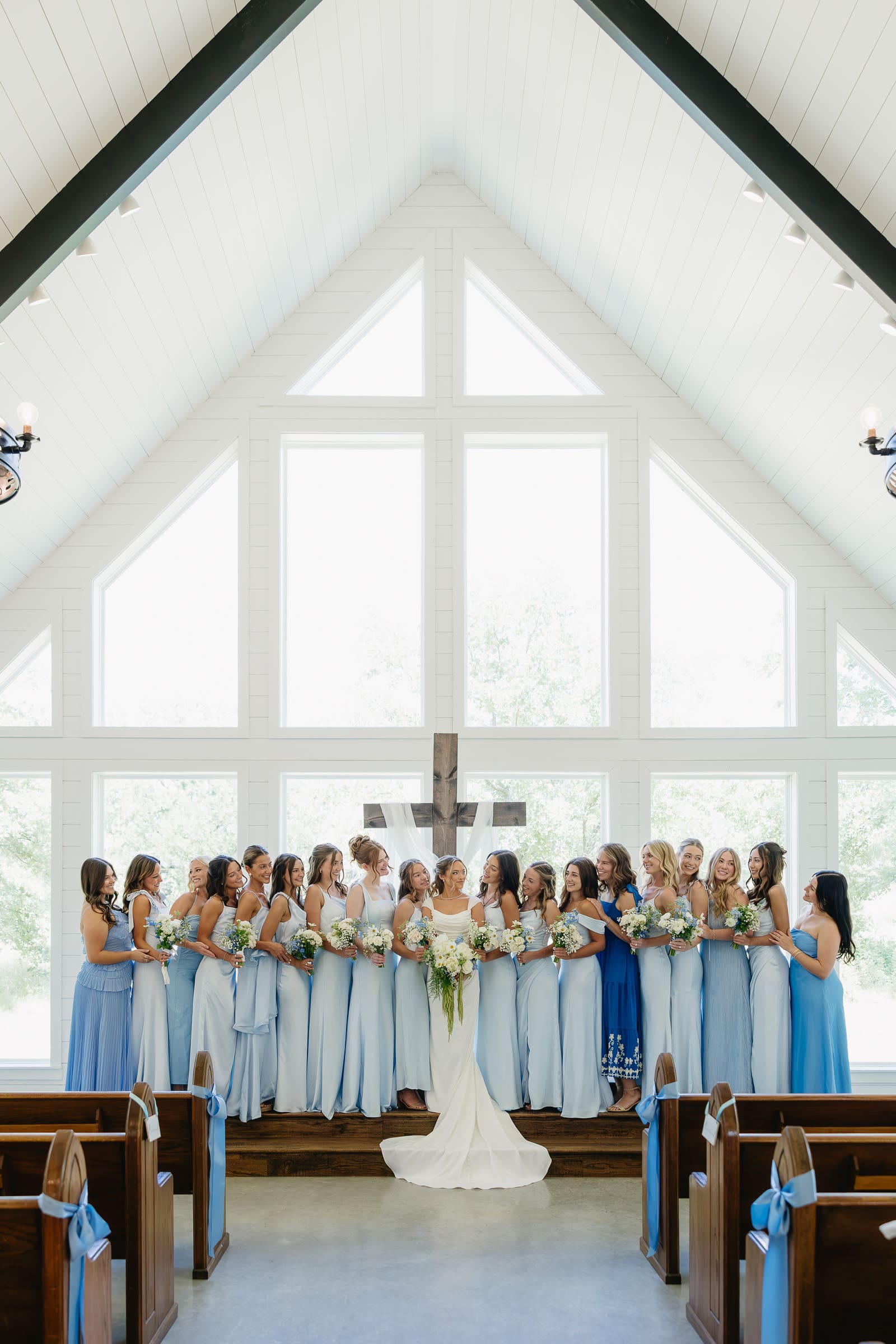 Bride with her bridesmaids in soft blue dresses inside The Barn at Paradise Place chapel